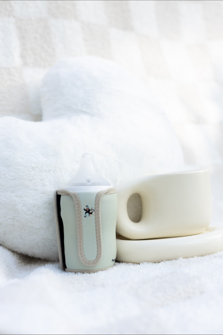 Mint Little Gripsters bottle sleeve styled on a soft blanket
