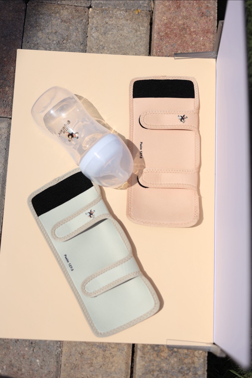 Mint and blush Little Gripsters sleeves laid out with a bottle